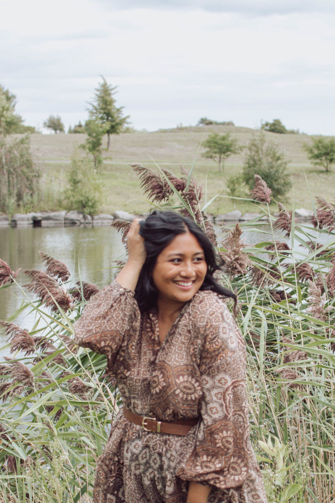 Canadian mommy blogger, Lisa Favre, posing in front of pampas wearing a belted tunic, made of light, airy material.