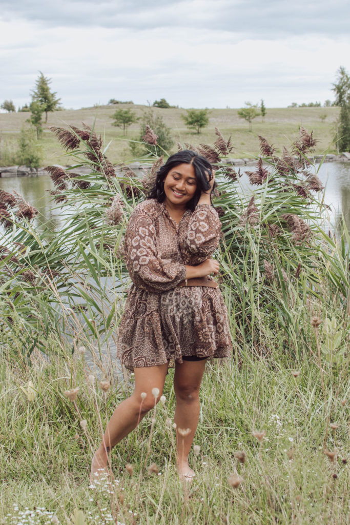 Canadian mommy blogger, Lisa Favre, posing in front of pampas wearing a belted tunic, made of light, airy material.