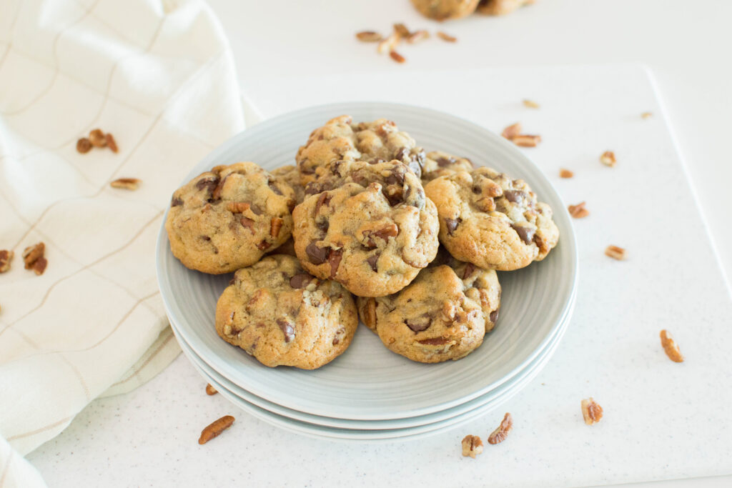 A plate of butter pecan cookies, surrounded by pecans on the table, ready to be served