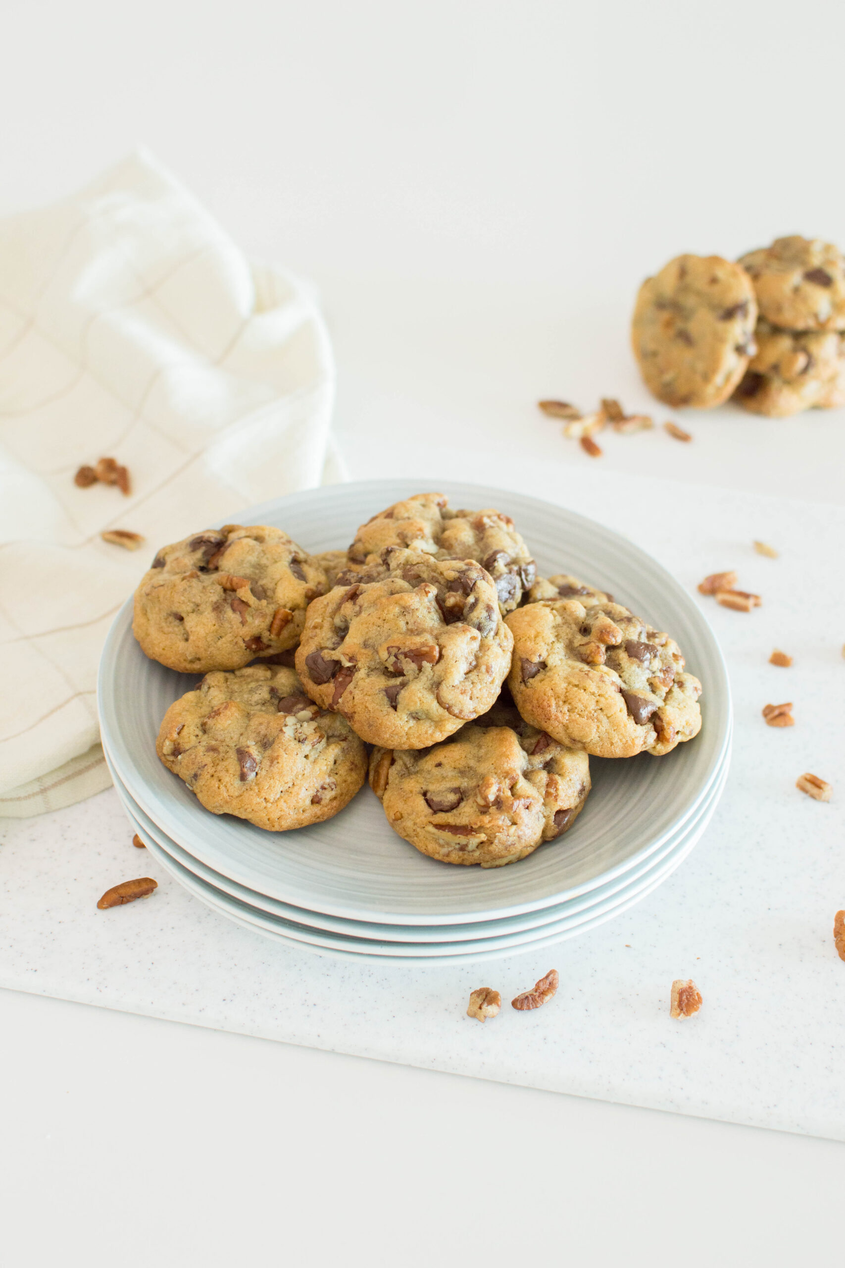 A plate of butter pecan cookies, surrounded by pecans on the table, ready to be served