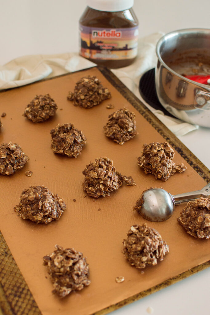 Scooped mounds of no-bake Nutella cookie dough set on a parchment-lined baking sheet.