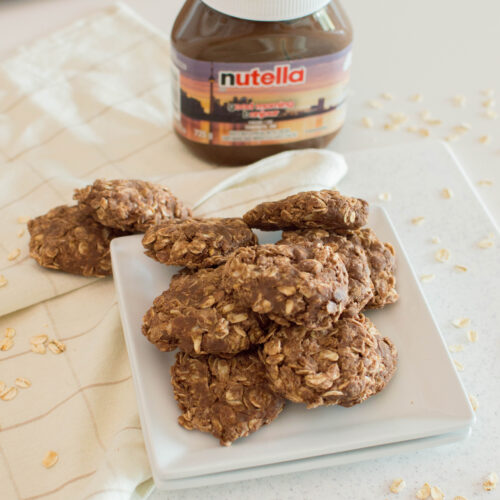 Stack of no-bake Nutella cookies on a white plate next to a jar of Nutella.