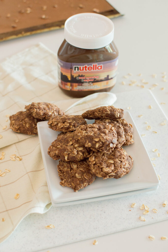 Stack of no-bake Nutella cookies on a white plate next to a jar of Nutella.