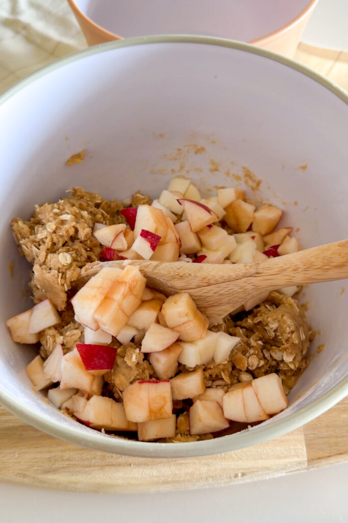 Stirring apple pieces into cookie dough for apple crumble cookies.