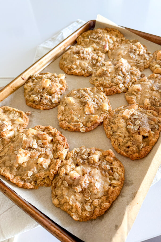 Freshly baked apple crumble cookies on a baking tray, golden and crumbly.