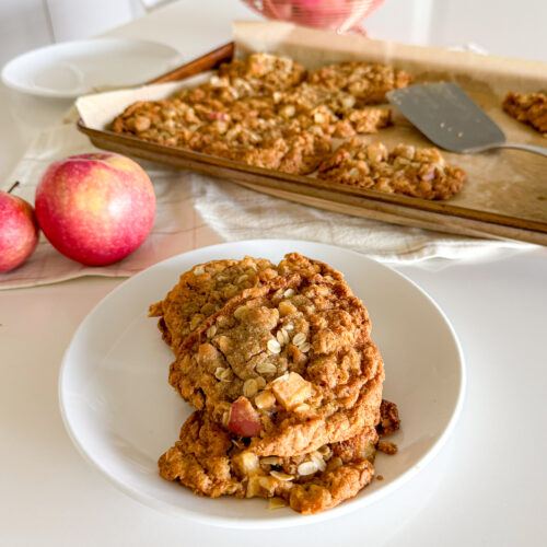 Apple crumble cookie served on a white plate with apples in the background.