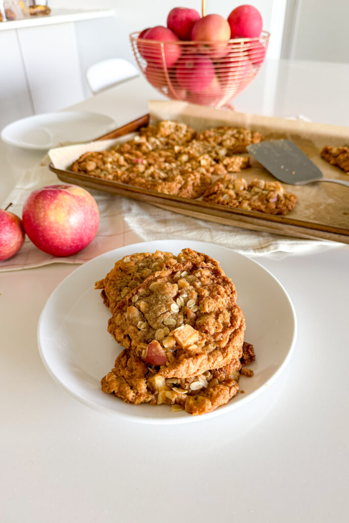 Apple crumble cookie served on a white plate with apples in the background.