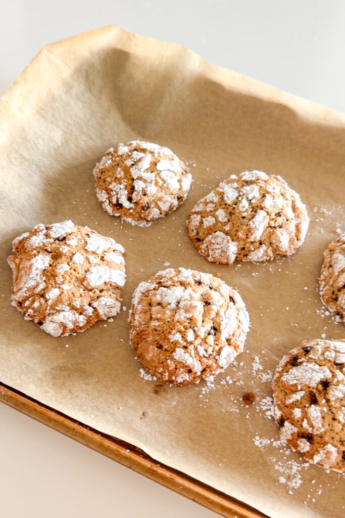 Freshly baked Coffee Crinkle Cookies with a soft crackle on parchment paper.