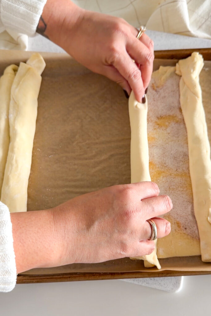 Rolling the puff pastry from both sides to form the classic palmier shape.