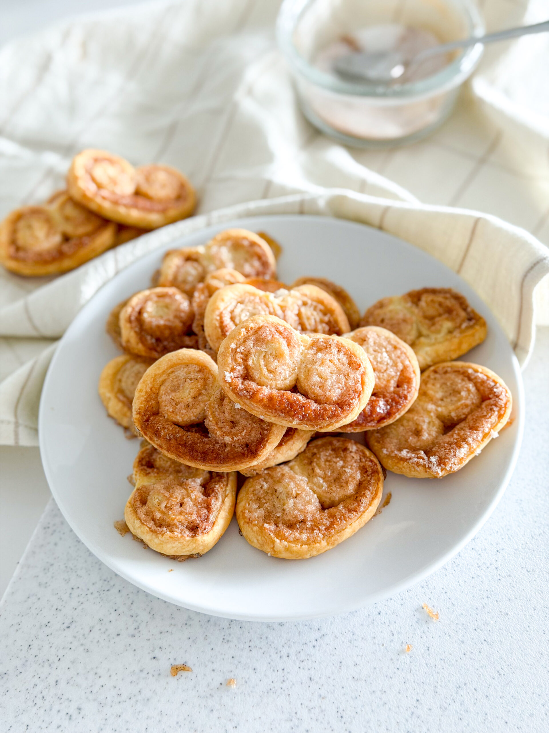 A plate of baked cinnamon palmiers arranged in a small pile.