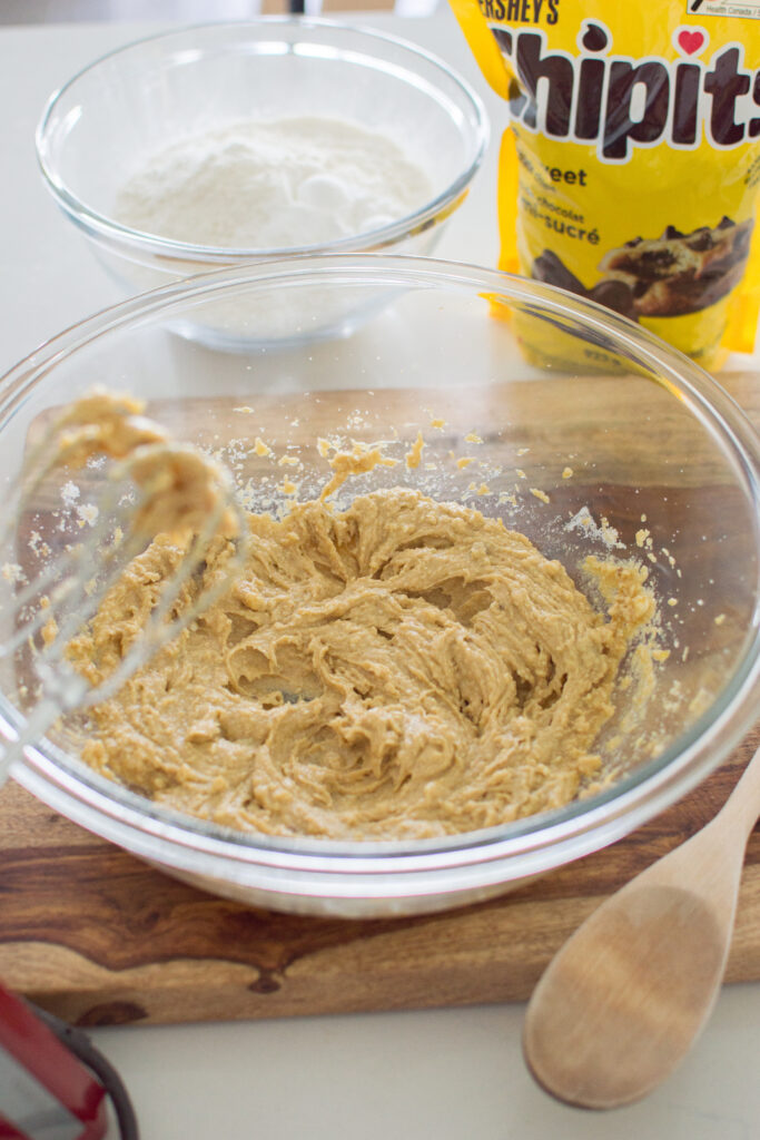 Cookie dough being mixed in bowl for oversized chocolate chip cookies