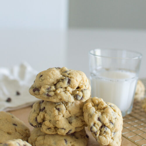 Soft oversized chocolate chip cookies stacked on parchment paper