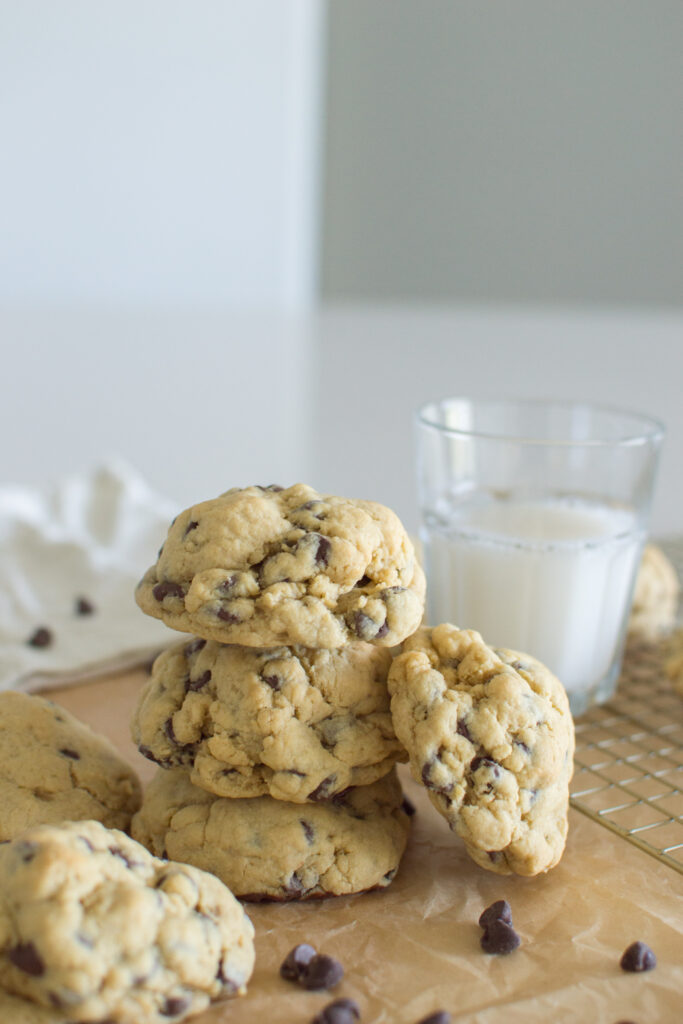 Soft oversized chocolate chip cookies stacked on parchment paper